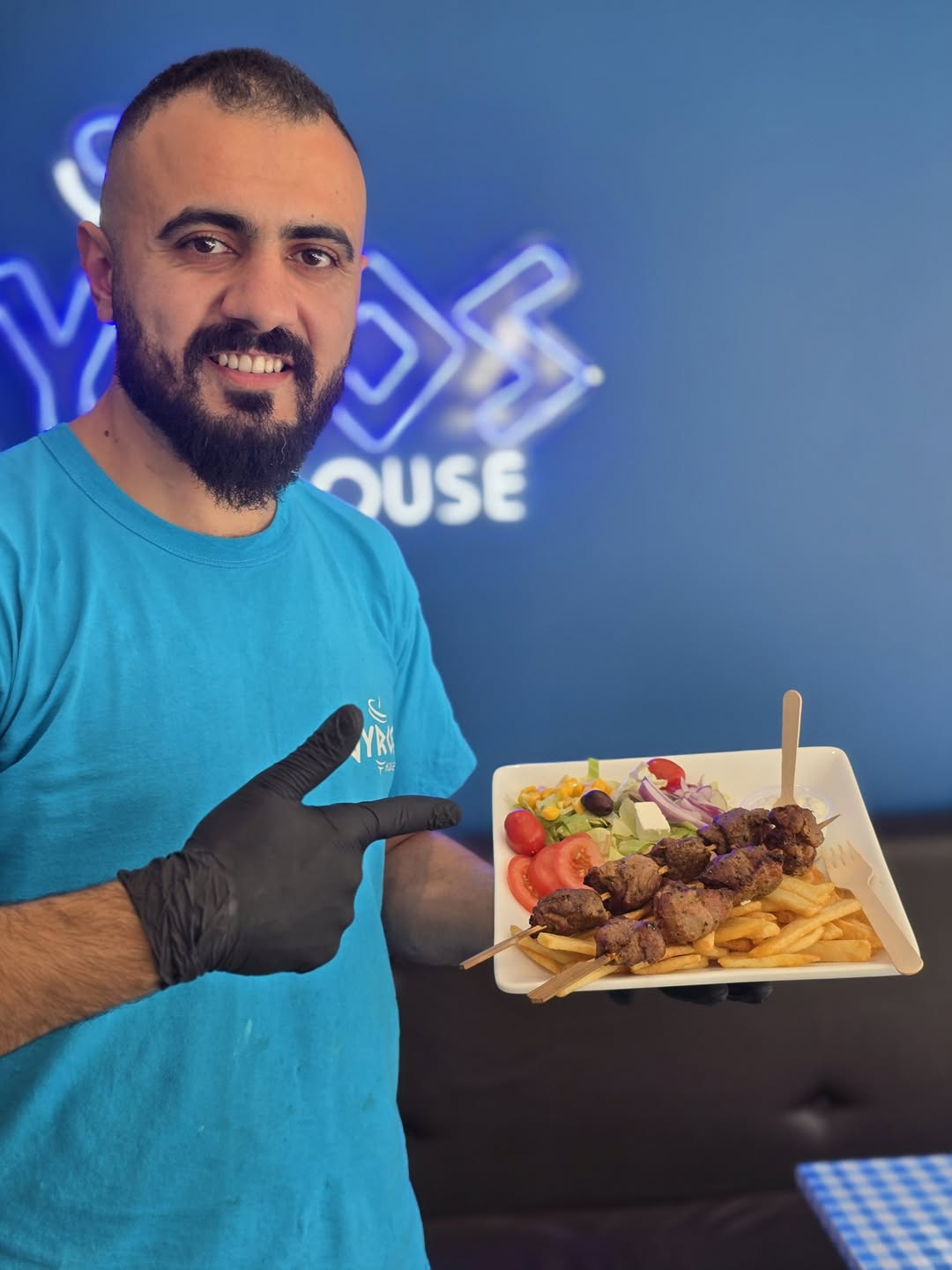 Ansatt som viser frem en ferdig souvlaki-tallerken